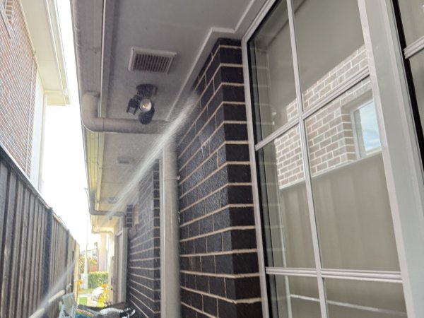 PestGuard Sydney technician applying a perimeter pest spray along the side of a brick home in Western Sydney